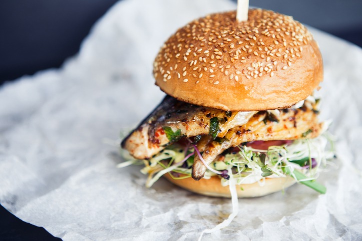 Fishburger on the butter-paper on the black background