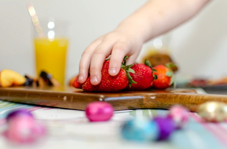 a toddler’s hand on strawberries