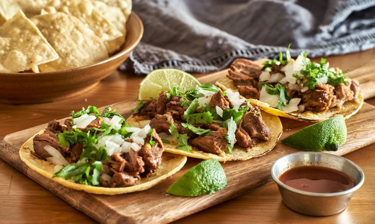three carne asada mexican street tacos in corn tortilla with lime