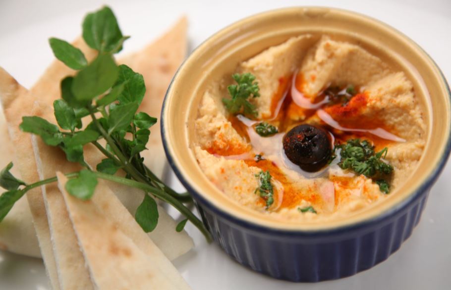 A bowl of hummus with slices of bread