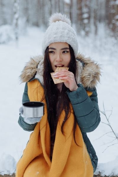 A woman in winter clothes eating crackers