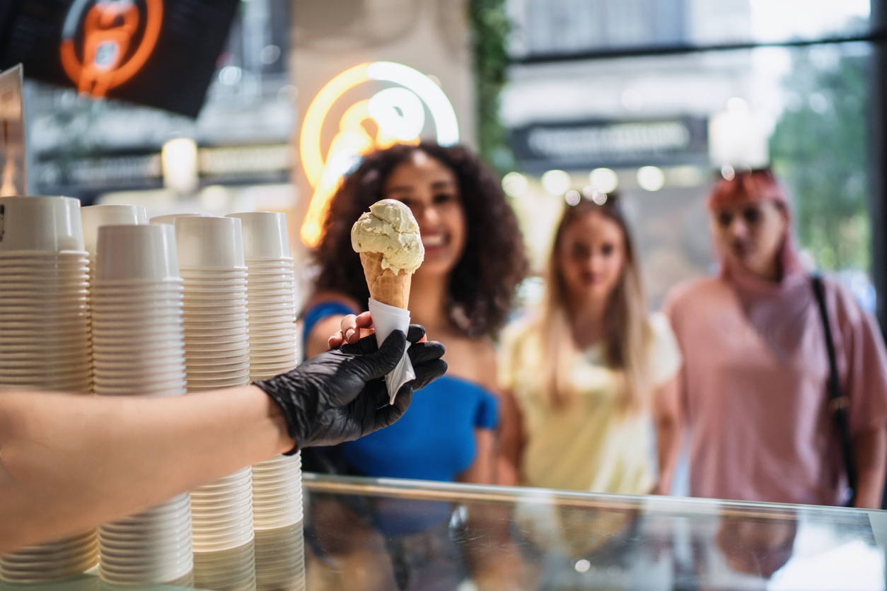 Ice cream shop worker serving ice cream cone to young women