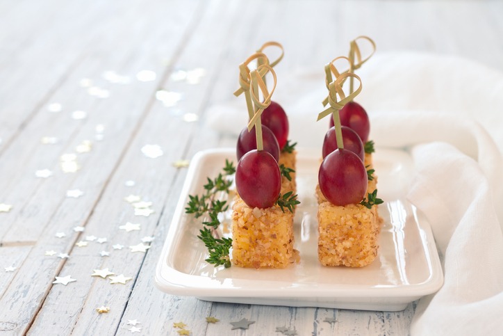 Canape with pink grapes and cheese in a nut breaded, on wooden skewers