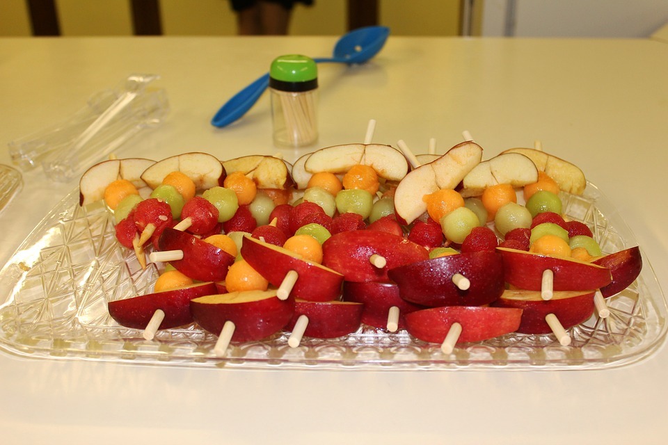 some fruit and cheese kabobs on a glass serving plate