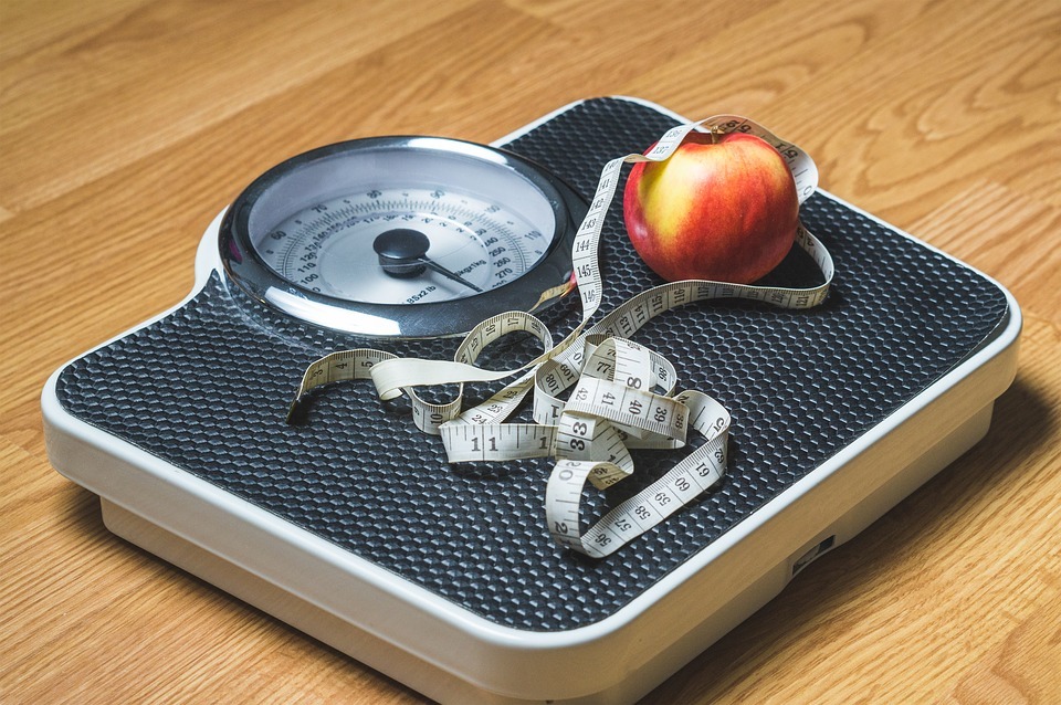 a weighing scale with a measuring tape and an apple on top