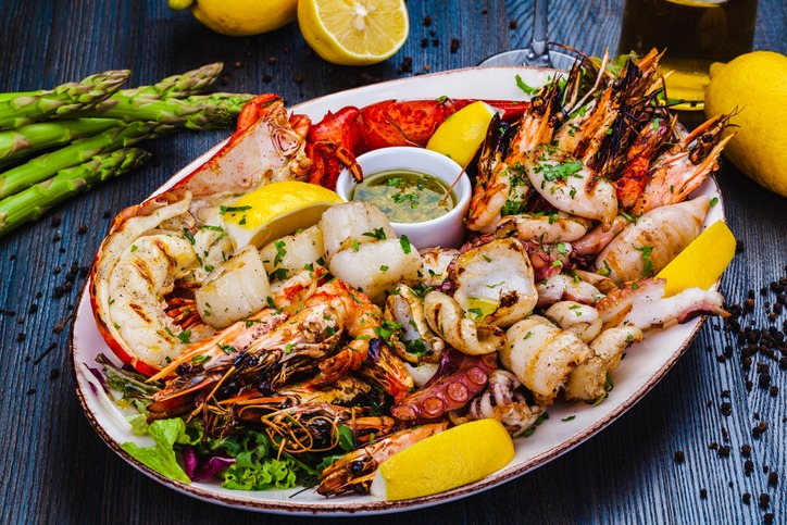 Seafood platter. Grilled lobster, shrimps, scallops, langoustines, octopus, squid on white plate