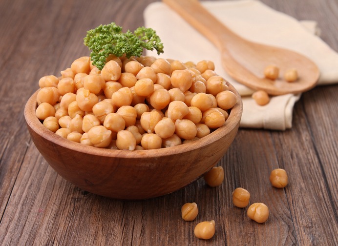 Wooden bowl overflowing with chickpeas topped with parsley