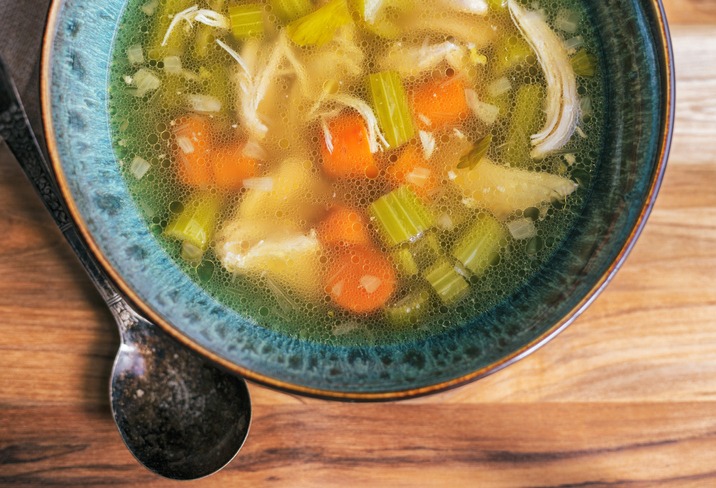 Bowl of chicken soup, shot directly above. Wooden background with copy space.