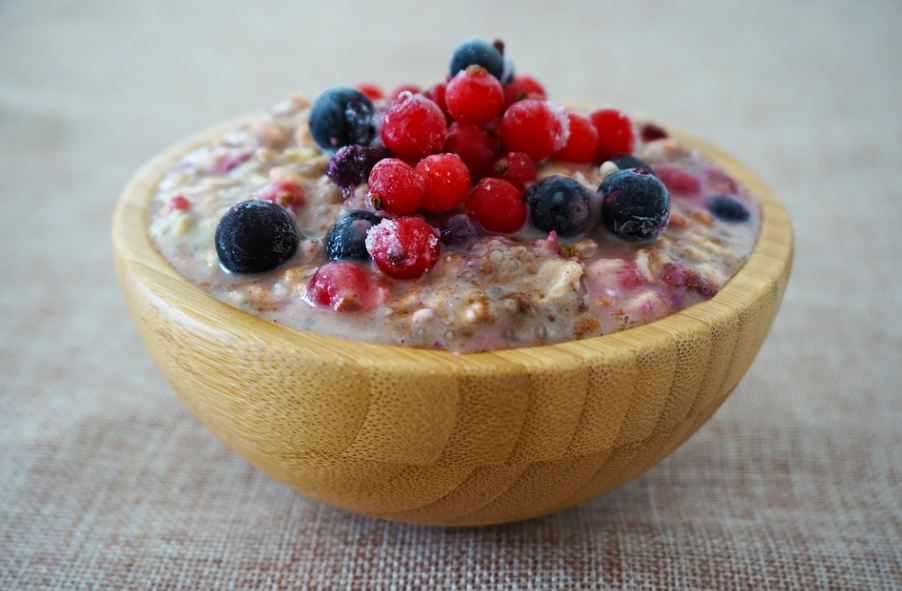 A wooden bowl of porridge topped with fruits