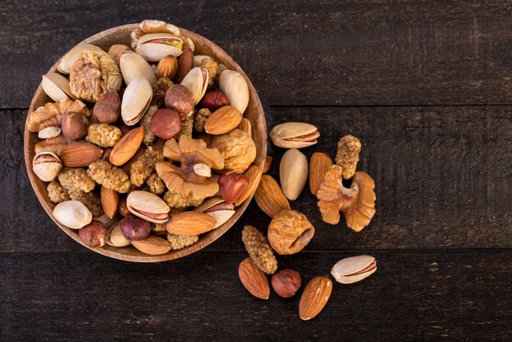 Organic Raw Nuts Mix Of Pistachios, Almonds, Walnuts, Dried Mulberries, Dried Figs And Hazelnuts On Wooden Plate And Table Background
