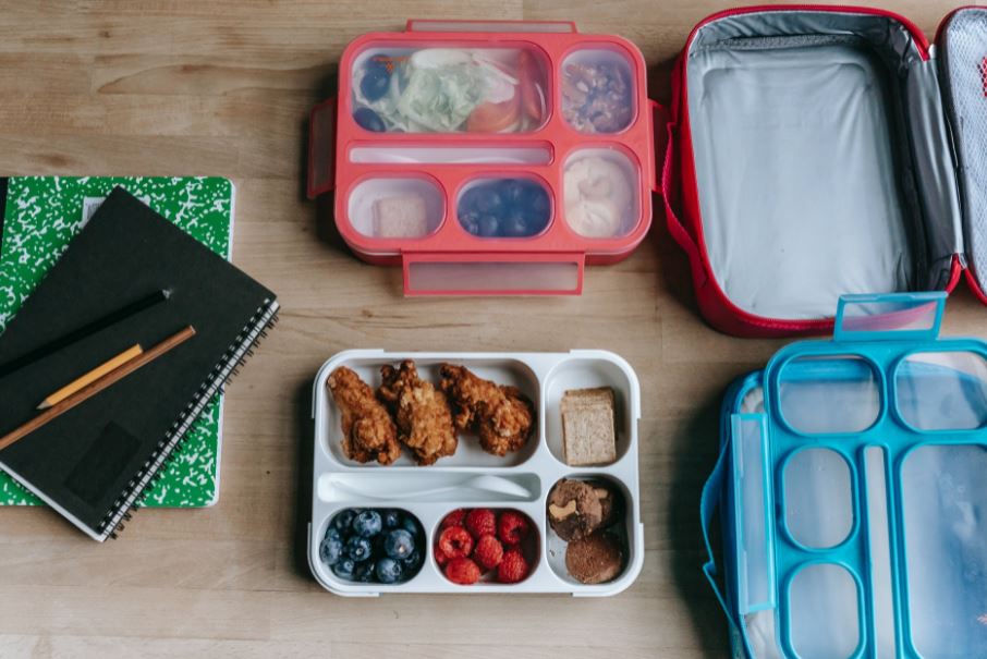 Two lunchboxes with healthy snacks and a notebook by the side
