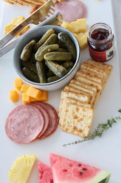 Baked cheese crackers with a bowl of pickles and sliced ham on the table