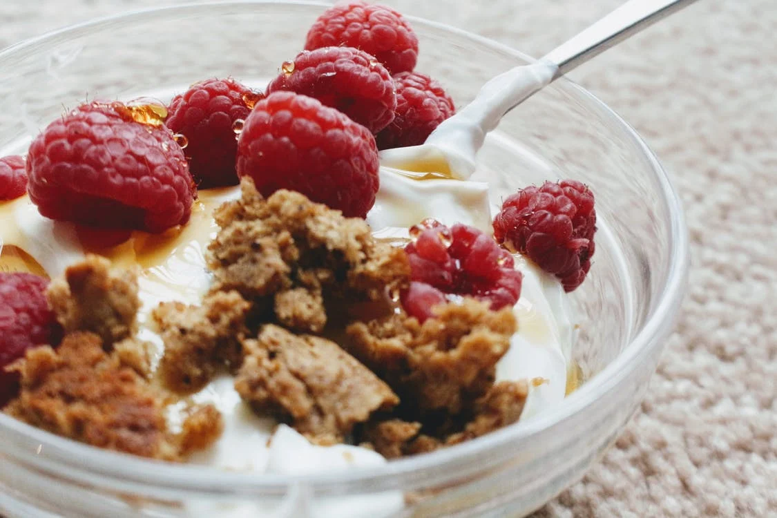 A bowl of Greek yogurt with raspberries and biscuit crumb
